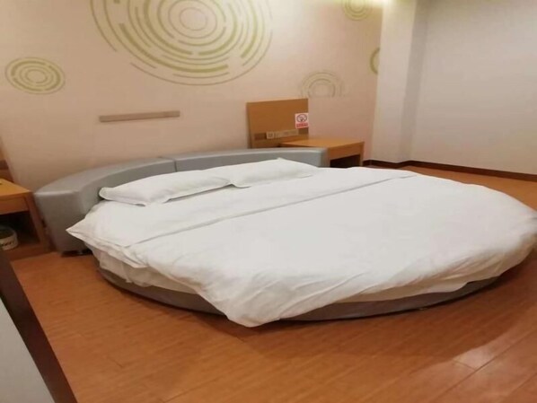 Cama bem arrumada em quarto de hotel, com design de parede circular e placa de proibido fumar.