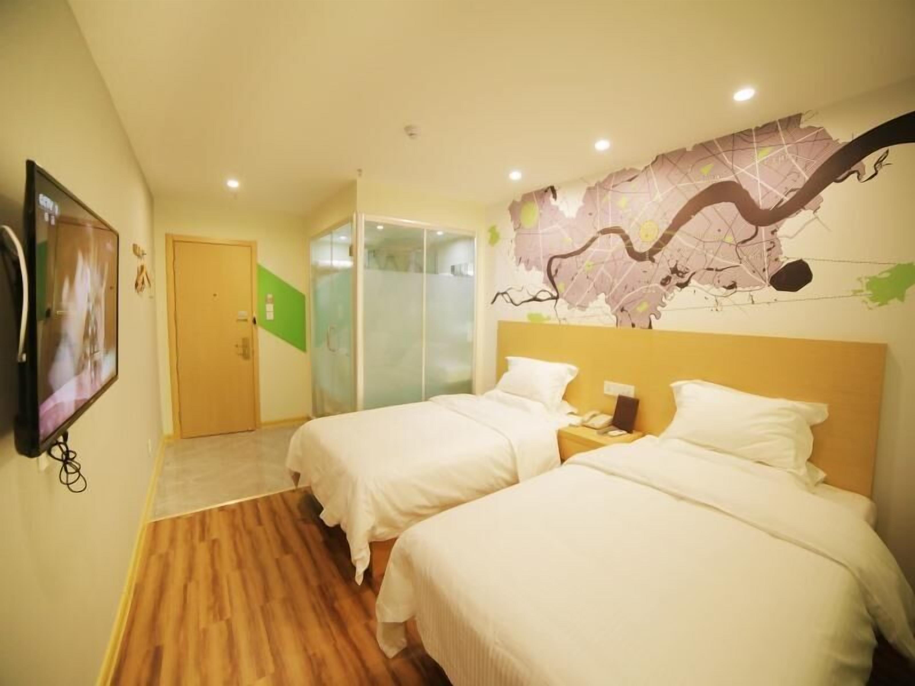 A hotel room with two beds, a television, a wardrobe, and a map mural on the wall.
