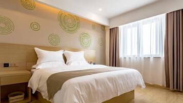 A modern hotel room with a large bed, a bedside table, and a headboard.