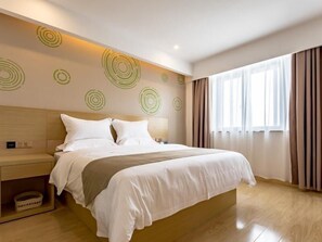 Una habitación de hotel moderna con una cama grande, cabecera de madera, mesita de noche con lámpara y un ventanal con cortinas.