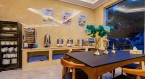 A dining area with a table, chairs, a buffet counter, and a wall with posters. - Shell Hotel (Wuxi)