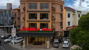 A multi-story hotel with a prominent red sign at the entrance. - Shell Hotel (Wuxi)