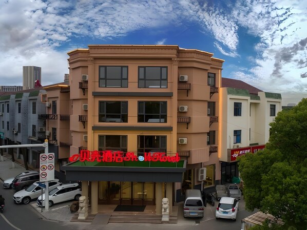 A multi-story hotel with a prominent red sign at the entrance. - Shell Hotel (Wuxi)