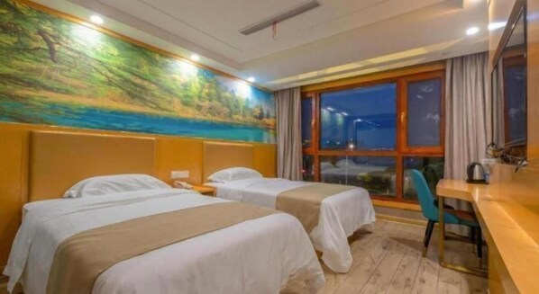 A hotel room with two beds, a desk, a chair, and a large window.