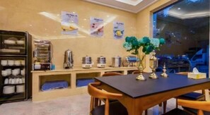 A dining area with a table, chairs, a buffet counter, and a wall with posters. - Shell Hotel (Wuxi)