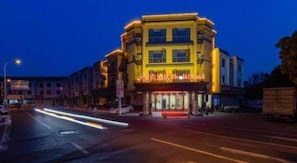 A multi-story building with a ground-floor commercial space, a visible entrance, and a parking area.