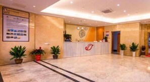 A hotel reception area with a marble floor, a reception desk, and potted plants. - Shell Hotel (Wuxi)