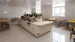 A modern kitchen with a central island, wooden tables, and chairs, and large windows providing natural light. - Shell Changzhou Wujin District Chunqiu Yancheng University Mingxin East Road Hotel (Changzhou)