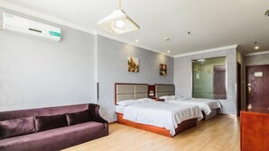 Une chambre d’hôtel avec un plancher en bois, un lit avec une literie blanche, un canapé violet et un luminaire au plafond.