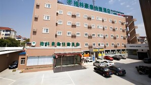 Un hôtel à plusieurs étages, doté d’une façade sobre, de nombreuses fenêtres et d’un parking où sont stationnées plusieurs voitures.