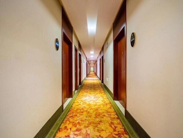 A hotel hallway with a carpeted floor and wooden doors. - Greentree Inn Shanghai East Xietu Road Jiuyuan Express Hotel (Shanghai)