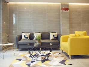 A modern living area with a grey sofa, yellow armchair, and a round coffee table with a plant.