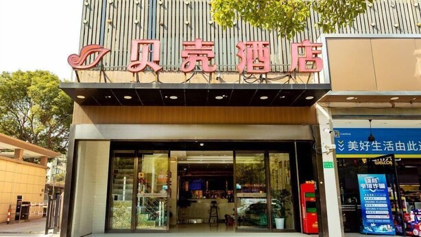 A hotel entrance with a modern facade, large glass doors, and a visible interior with seating and a counter. - Shell Shanghai Baoshan District Tieli Road Subway Station Tiefeng Road Hotel (Shanghai)