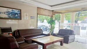 A lobby with leather sofas, a coffee table, and a painting on the wall. - Shells Shanghai Minhang District Pujiang Town Zhuyuan Road Hotel (Shanghai)
