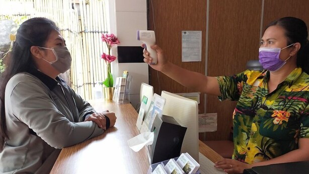 A reception desk with a computer, a phone, and a plastic container with cards. - City Garden Bali Dwipa Hotel (Kuta)