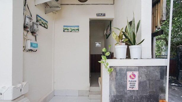 A reception area with a sign indicating a toilet, electrical panels, potted plants, and a sign requesting to wash hands. - City Garden Bali Dwipa Hotel (Kuta)