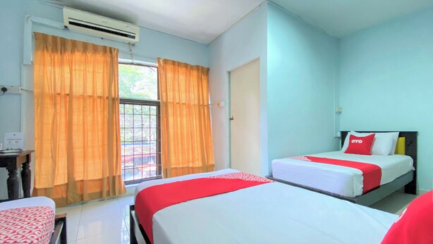 A hotel room with two beds, a window with curtains, an air conditioning unit, and a door. - OYO 90159 Zahaar Hotel (George Town)