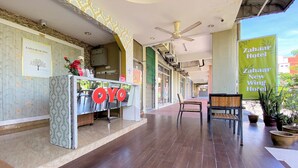 A reception area with a counter, a ceiling fan, and a sign for Zahaar Hotel. - OYO 90159 Zahaar Hotel (George Town)