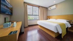 A hotel room with a wooden bed, a desk with a coffee cup, a window with curtains, and a painting on the wall. - Greentree Alliance Shanghai West Shuichan Road Hotel (Shanghai)