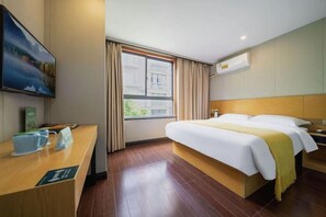 A hotel room with a wooden bed, a desk with a coffee cup, a window with curtains, and a painting on the wall. - Greentree Alliance Shanghai West Shuichan Road Hotel (Shanghai)