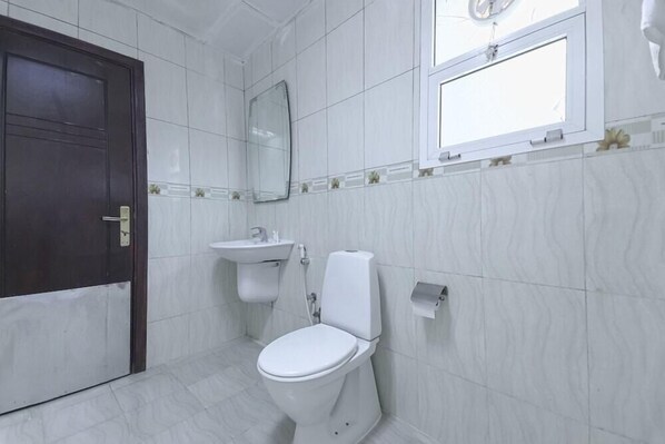 Un baño con inodoro, lavamanos, espejo y ventana.