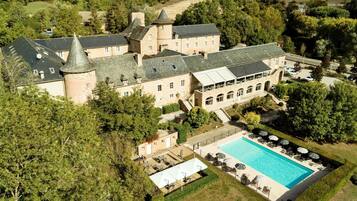 Vue aérienne d’un vaste domaine comprenant une piscine, plusieurs bâtiments et de nombreux espaces verts.