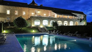 A large stone building with a swimming pool and outdoor seating area.