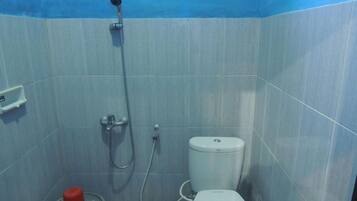 A small bathroom with a toilet, a shower, and a red bucket.