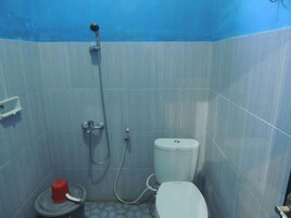 Un baño pequeño con inodoro, ducha y un balde rojo.