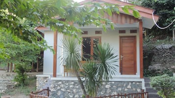 A small house with a stone facade, wooden door, and a small porch with a railing.