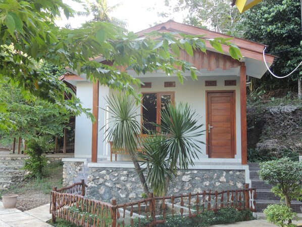 A small house with a stone facade, wooden door, and a small porch with a railing.