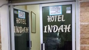 Ein Hotel Eingang mit Glastüren und einem Schild mit der Aufschrift 'HOTEL INDAH'.