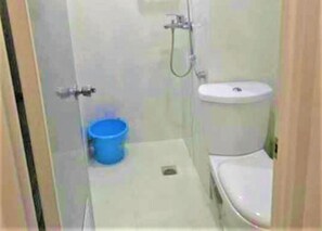 Un baño pequeño con inodoro, lavamanos y un cubo azul.