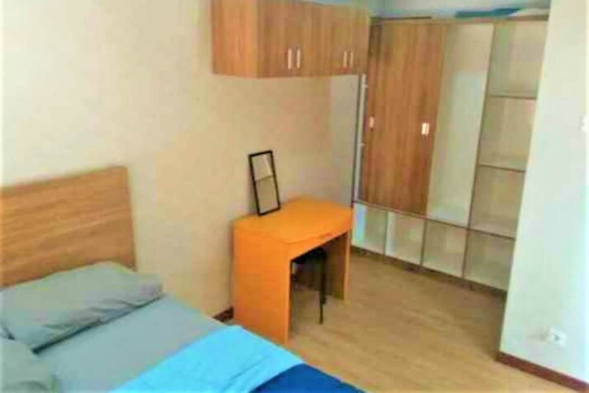 A bedroom with a bed, a desk, and a wardrobe.