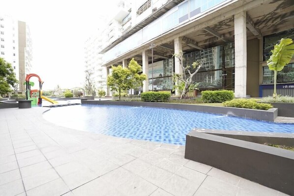 A swimming pool area with a modern building in the background. - Apartment Gateway Pasteur Nazra Property (Cimahi)