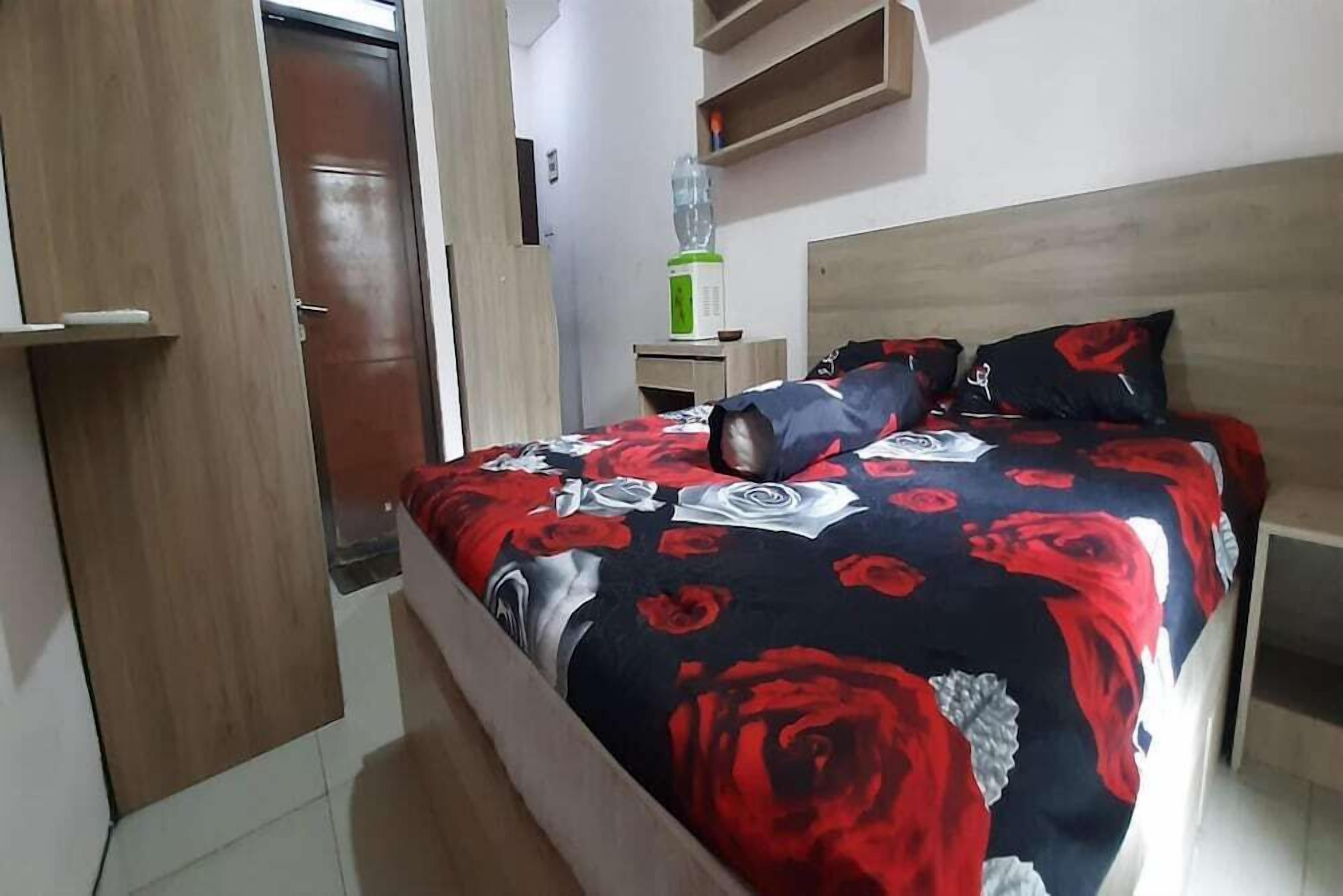 A bedroom with a bed, a wooden headboard, a nightstand, a water dispenser, and a wardrobe.