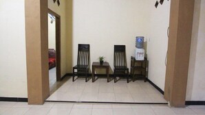 A hallway with four wooden chairs, a small table with a plant, and a water dispenser. - Homestay Sekar (Borobudur)