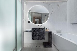 Un bagno moderno con un lavabo in marmo, un grande specchio e una vasca da bagno freestanding.
