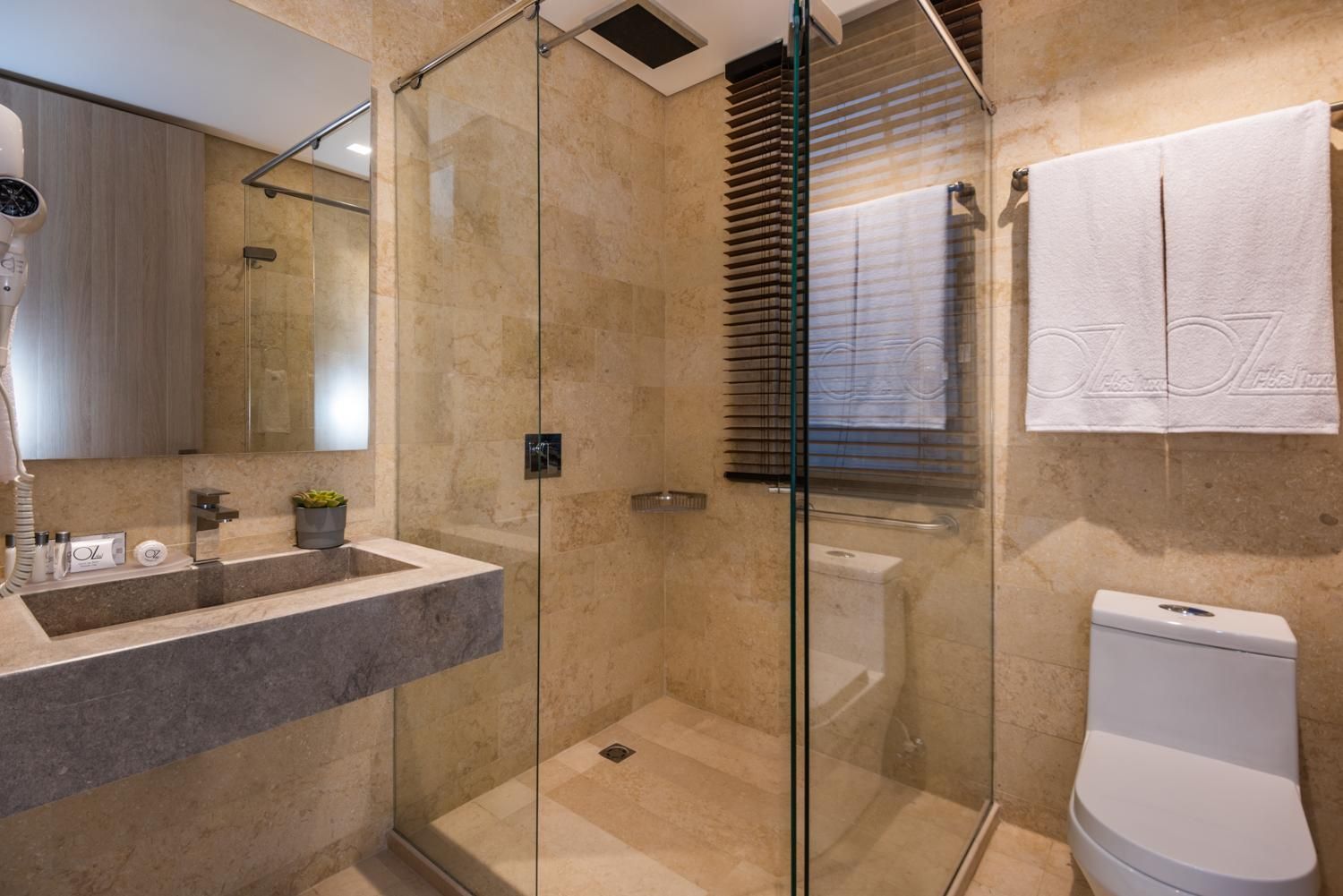 A modern bathroom with a glass-enclosed shower, a sink with a marble countertop, and a toilet.