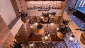 A modern hotel lobby with a stone wall, hanging baskets with plants, and a wooden reception desk. - Hotel OZ Luxury (Cartagena (CO))