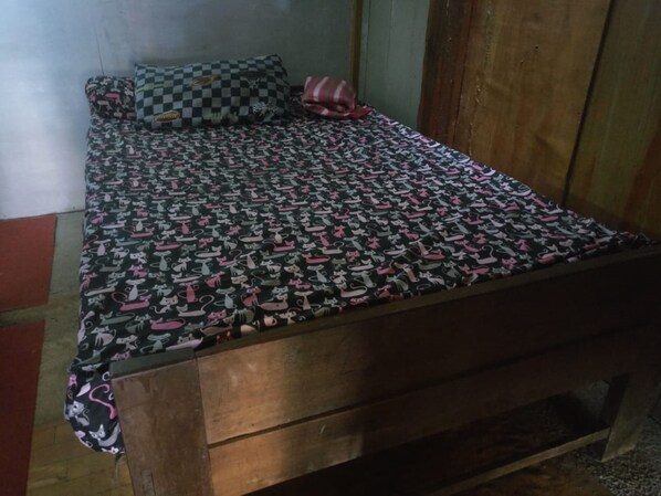 A single bed with a patterned bedspread, a checkered pillow, and a striped pillow. - Homestay An-nur (Berbah)