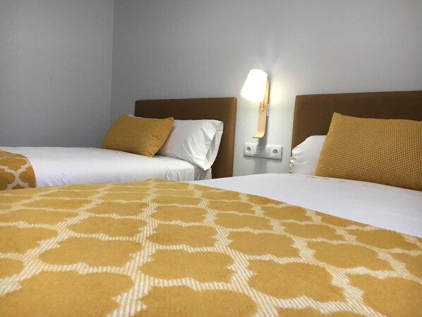 Une chambre d’hôtel avec deux lits, chacun recouvert d’une couvre-lit à motifs, agrémenté de draps blancs et d’oreillers assortis.
