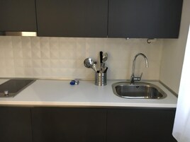 Una cocina con un lavamanos de acero inoxidable, armarios oscuros y un salpicadero de azulejos.