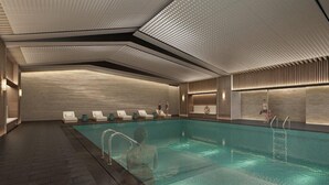 Une piscine intérieure moderne dotée d’un plafond au design géométrique, de chaises longues et d’un espace piscine dégagé.