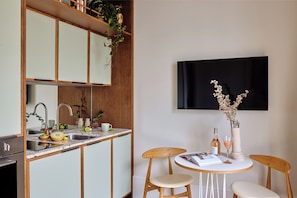 A modern kitchen with a built-in island, a dining area with a round table and chairs, and a flat-screen TV mounted on the wall. - Turing Locke, Eddington (Cambridge)