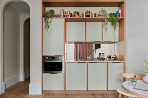 A compact kitchen with a built-in oven, a sink, and a countertop with various items.