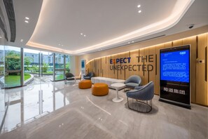 A modern lobby with a curved wall, seating area, and a digital display. - Holiday Inn Express Yibin (Yibin)