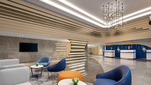 En moderne lobby med siddepladser, en receptionsdisk og en lysekrone.