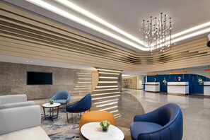 A modern lobby with seating, a reception desk, and a chandelier.