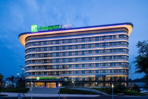 Un hotel moderno Holiday Inn Express con fachada curva, varios pisos y una entrada destacada.